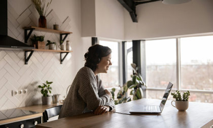 Mujer sonriendo mirando una laptop sobre una encimera