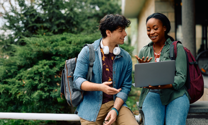 Hombre y mujer mirando una laptop al aire libre