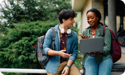 Hombre y mujer fuera de un edificio sosteniendo una laptop