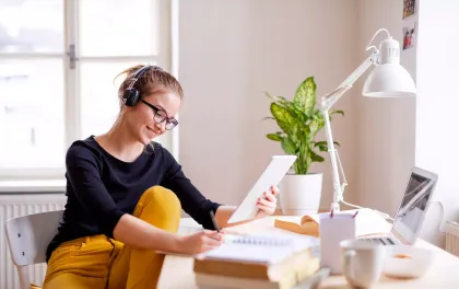 Mujer trabajando con una tablet y auriculares.
