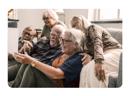 Grupo de personas mayores sonriendo y mirando una laptop