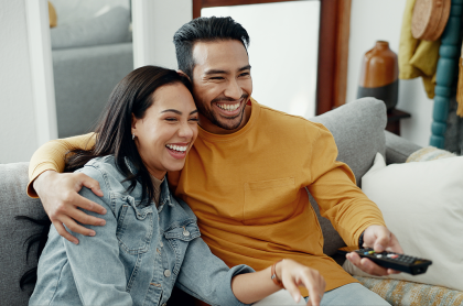 Pareja sonriendo y sosteniendo un control remoto