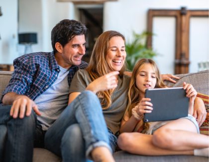 Familia sentada sobre un sofá, compartiendo una tablet