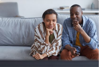 Un padre y una hija mirando TV en su casa.