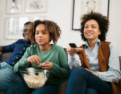 Una familia feliz sentada en un sillón mirando TV.