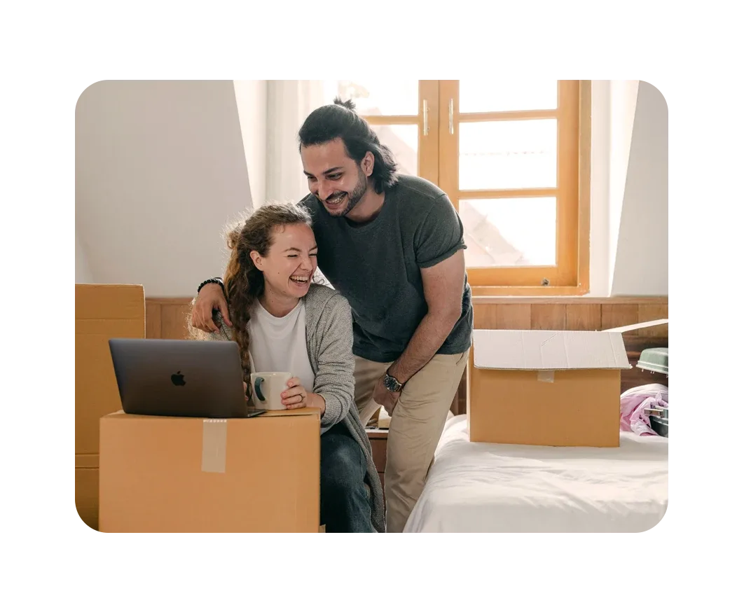 Una pareja ríe mientras utiliza una caja como mesa para instalar Internet de Breezeline en su nuevo hogar.