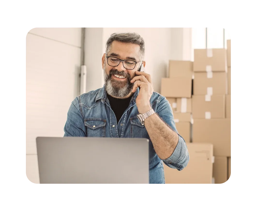 Un hombre coordina el traslado del servicio de Internet para el hogar de Breezeline a través del teléfono, cajas cercanas
