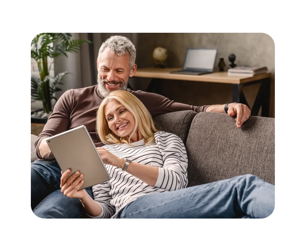 Pareja feliz en un sofá navegando por Internet en su tablet después de una mudanza sin complicaciones