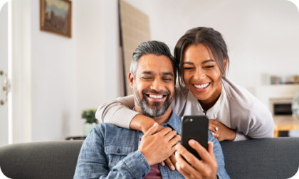 Hombre y mujer sonriendo mirando un teléfono móvil
