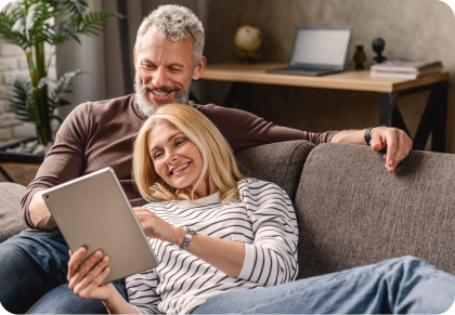 Una pareja mayor sonríe mientras miran una tablet