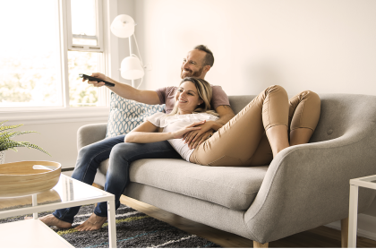 Pareja recostada en un sillón mirando TV