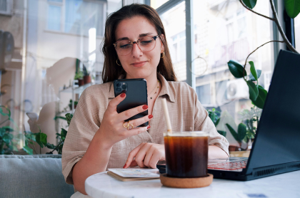 Joven sosteniendo un teléfono móvil en una cafetería