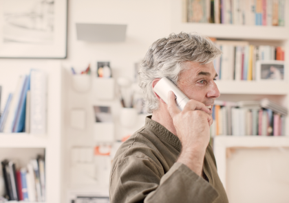 Un hombre habla por un teléfono fijo blanco
