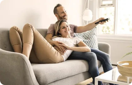 Una pareja viendo TV juntos en un sofá.