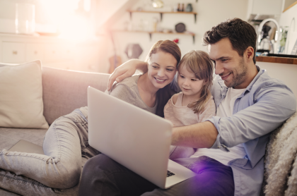 Familia mirando una laptop sentados en un sillón