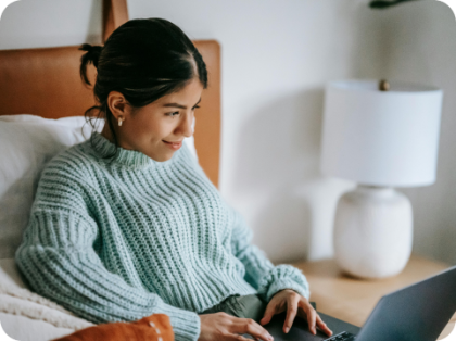 Mujer sentada en la cama con una laptop